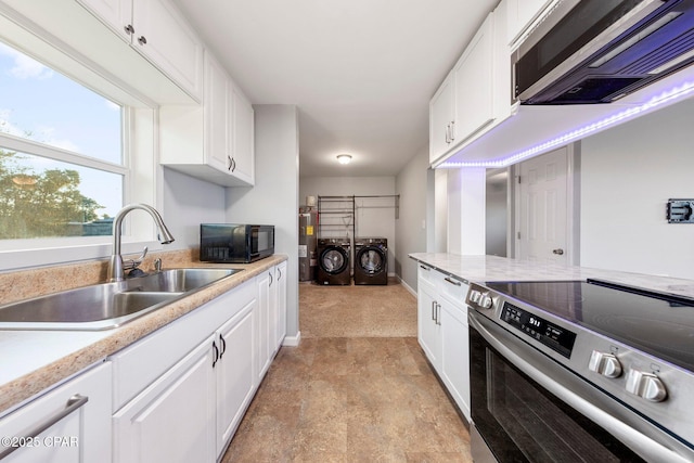kitchen featuring appliances with stainless steel finishes, a sink, light countertops, white cabinets, and washer and clothes dryer