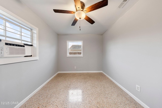 unfurnished room with visible vents, baseboards, ceiling fan, speckled floor, and cooling unit