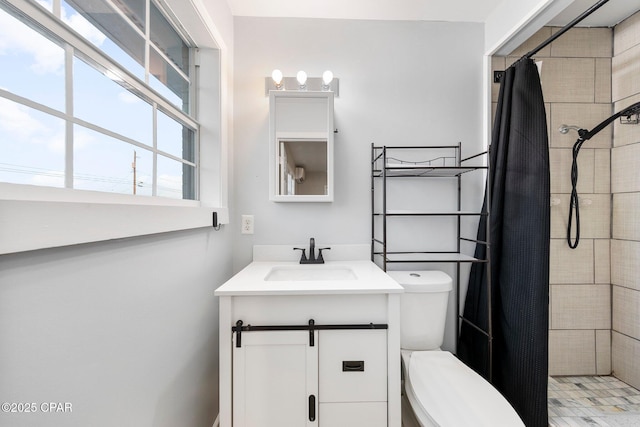 full bathroom featuring vanity, a tile shower, and toilet