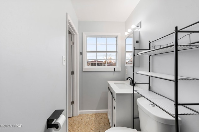 bathroom with vanity, baseboards, speckled floor, and toilet