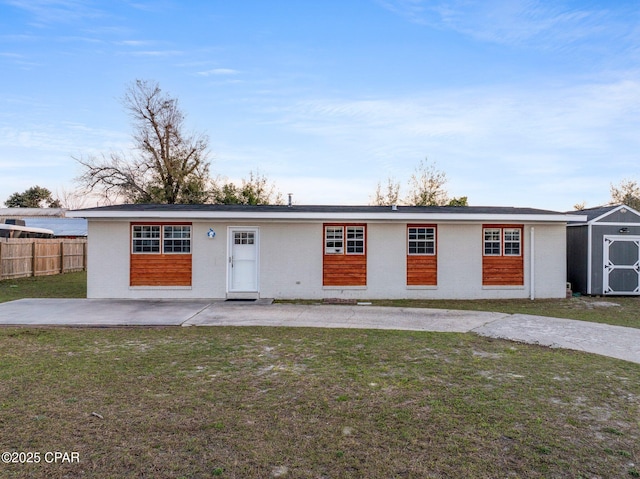 view of front of home with an outdoor structure, fence, a front yard, a patio, and a shed