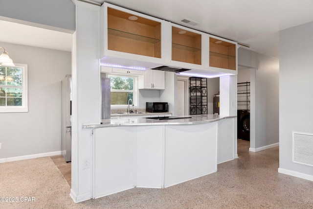 kitchen with light countertops, light speckled floor, baseboards, visible vents, and black appliances