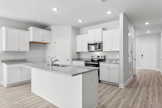 kitchen featuring appliances with stainless steel finishes, a kitchen island with sink, white cabinets, and a sink