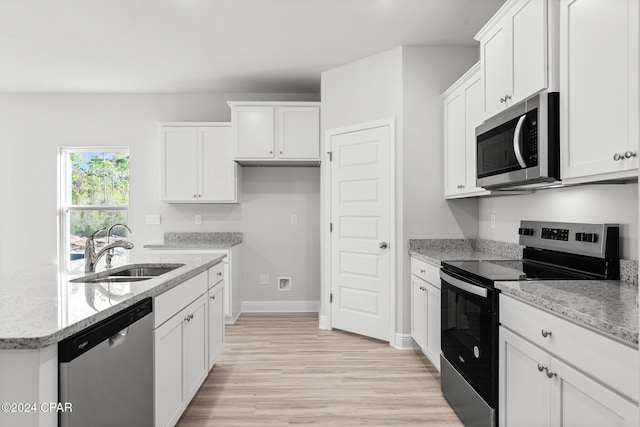 kitchen featuring stainless steel appliances, light stone counters, a sink, and white cabinetry