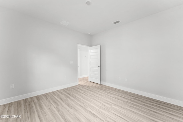 spare room featuring light wood-style floors, visible vents, and baseboards