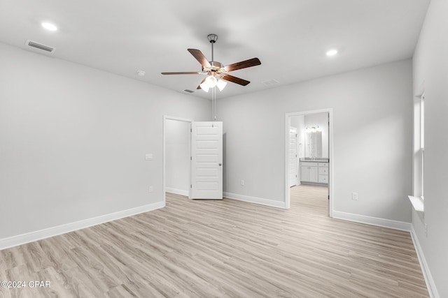 spare room with light wood-type flooring, visible vents, and baseboards