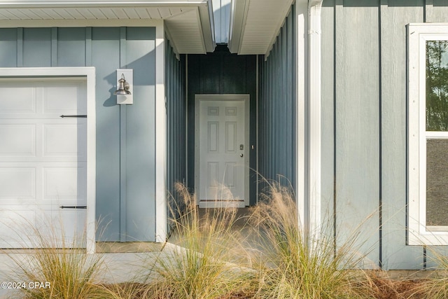 doorway to property with board and batten siding and a garage