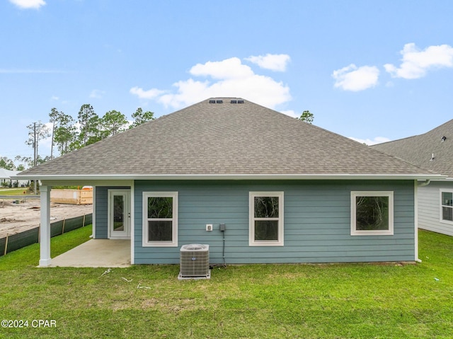 rear view of property with a yard, a shingled roof, and cooling unit