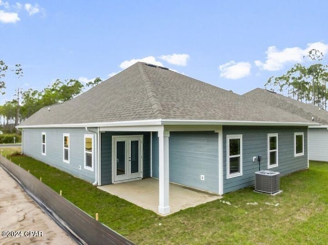 back of house with central AC, french doors, a lawn, roof with shingles, and a patio area