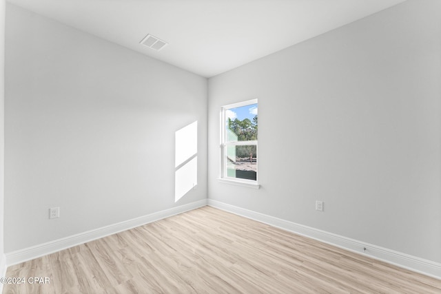 spare room featuring light wood-style floors, visible vents, and baseboards