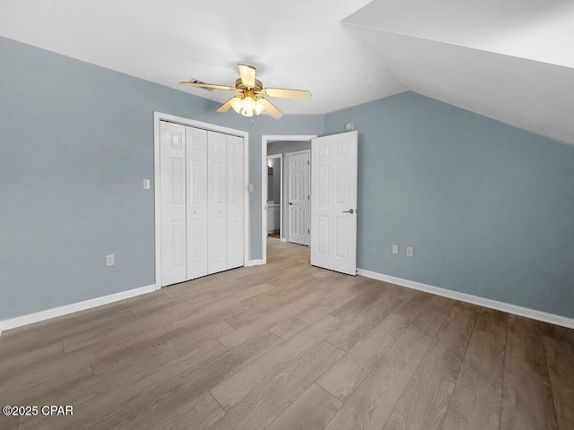 unfurnished bedroom featuring a closet, ceiling fan, vaulted ceiling, wood finished floors, and baseboards