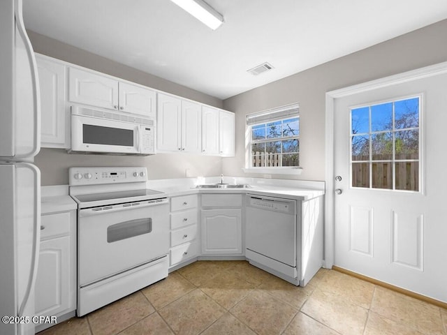 kitchen with white appliances, white cabinetry, visible vents, and a sink