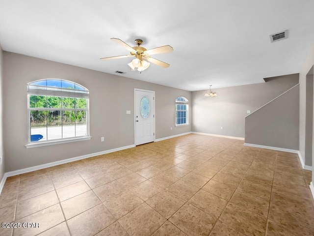 interior space featuring tile patterned floors, baseboards, visible vents, and ceiling fan with notable chandelier