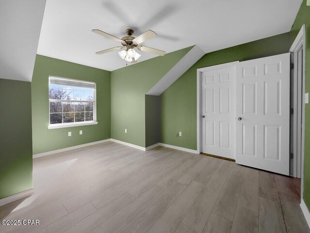 bonus room featuring ceiling fan, baseboards, vaulted ceiling, and wood finished floors