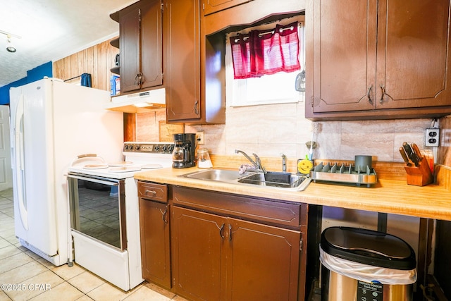 kitchen featuring white appliances, under cabinet range hood, light countertops, and a sink