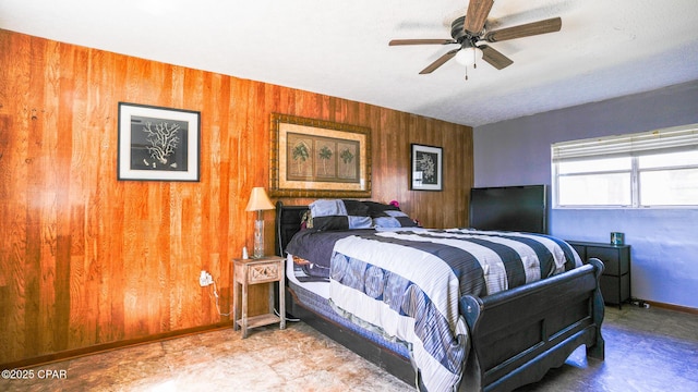 bedroom featuring wood walls, baseboards, and a ceiling fan