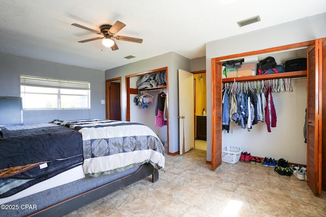 bedroom with ceiling fan, visible vents, and two closets