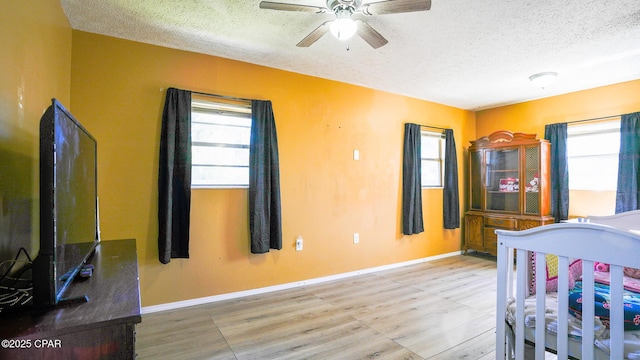 bedroom with multiple windows, a textured ceiling, and baseboards