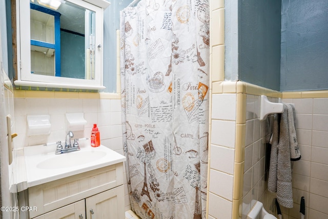 bathroom featuring curtained shower, wainscoting, vanity, and tile walls