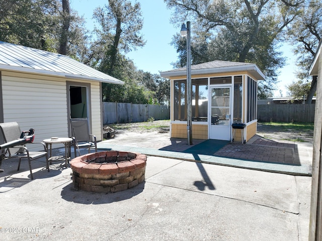 view of patio / terrace with an outdoor fire pit, a fenced backyard, and a sunroom