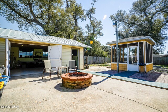view of patio with a sunroom, fence, and a fire pit