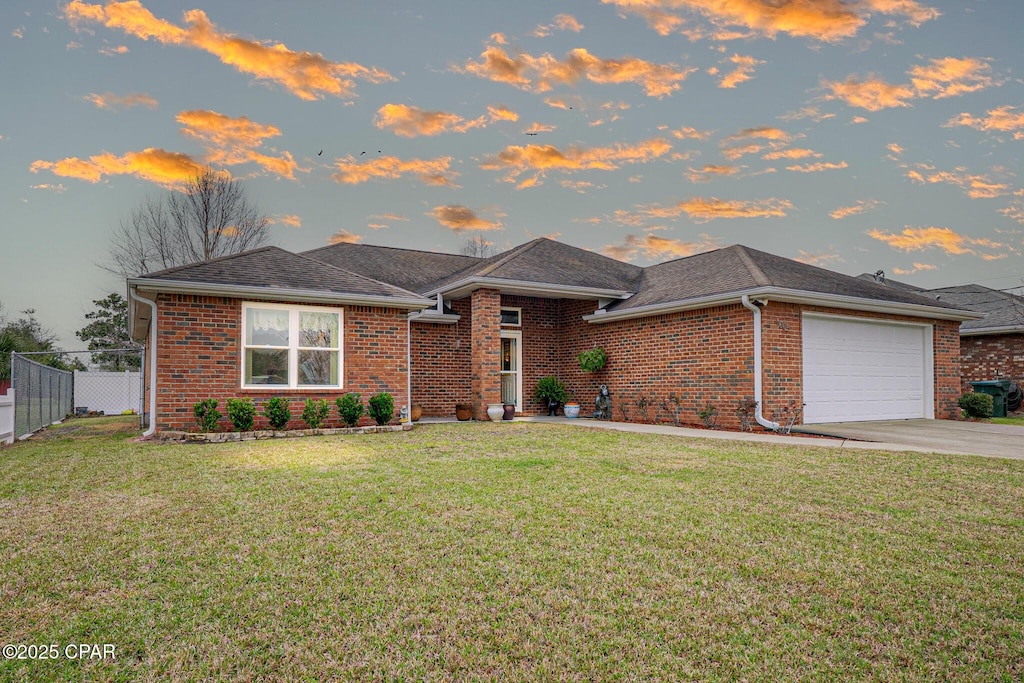 1005 E 10th St, Lynn Haven, FL 32444 - view of front of house featuring driveway, an attached garage, fence, a yard, and brick siding