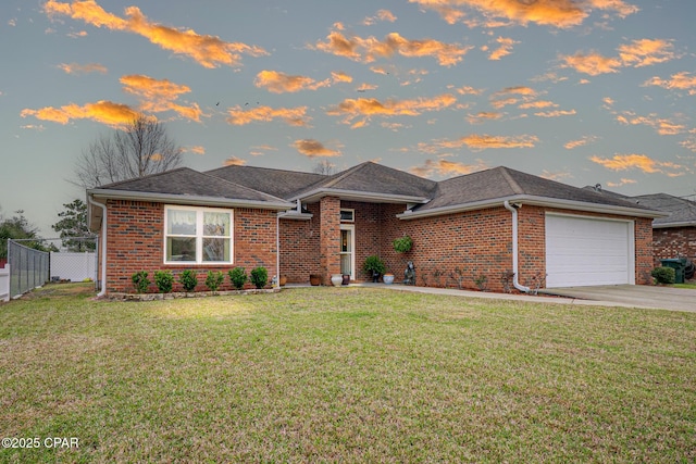 view of front of house featuring driveway, an attached garage, fence, a yard, and brick siding