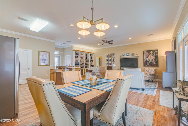 dining space with ornamental molding, a wealth of natural light, and light wood-style floors