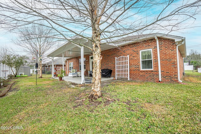 rear view of property with a patio area, brick siding, a yard, and fence