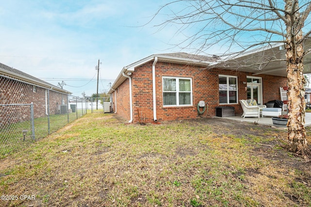 back of house featuring a patio area, brick siding, fence, and a lawn