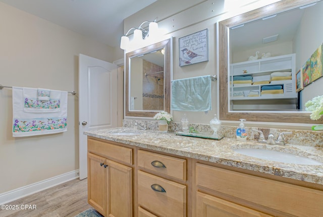 bathroom featuring double vanity, wood finished floors, a sink, and baseboards