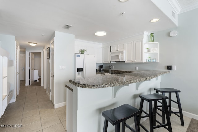 kitchen with open shelves, white cabinets, dark stone countertops, white appliances, and a peninsula