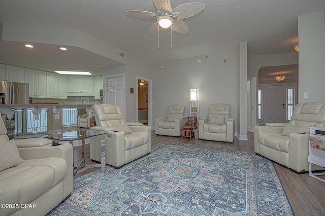 living area featuring recessed lighting, visible vents, a textured ceiling, and wood finished floors