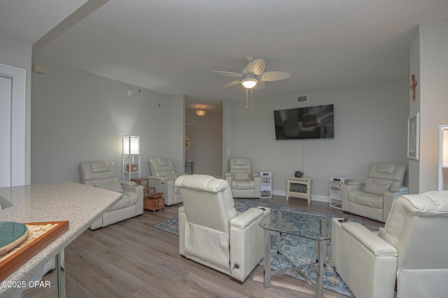 living room with visible vents, ceiling fan, light wood-style flooring, and baseboards