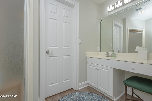 bathroom with baseboards, visible vents, wood finished floors, and vanity