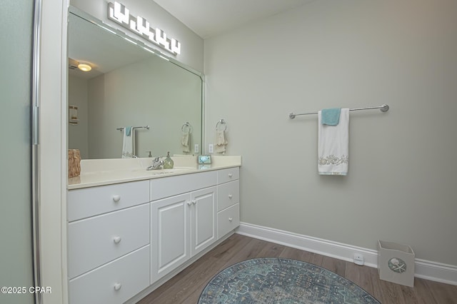 bathroom with wood finished floors, vanity, and baseboards