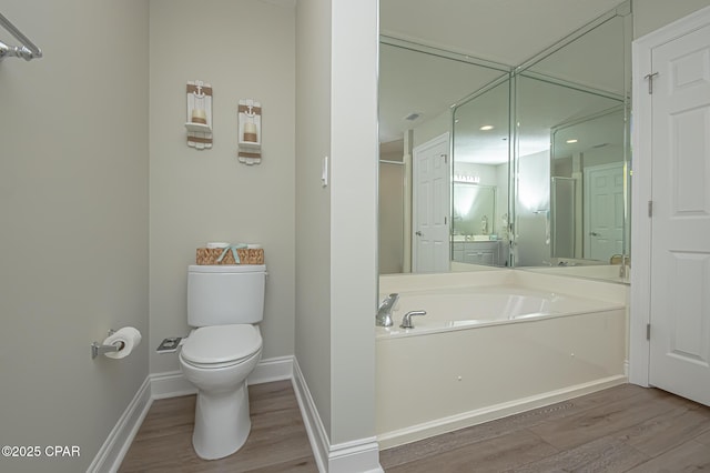 bathroom featuring visible vents, baseboards, toilet, wood finished floors, and a garden tub