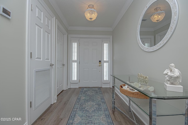 foyer featuring light wood finished floors, visible vents, and ornamental molding