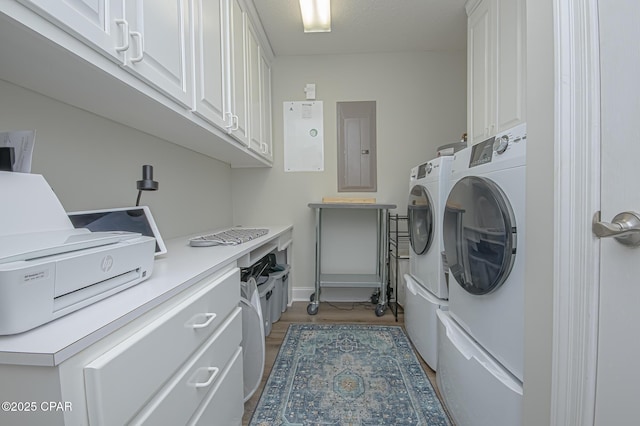 laundry room with light wood-style floors, washing machine and dryer, electric panel, and cabinet space