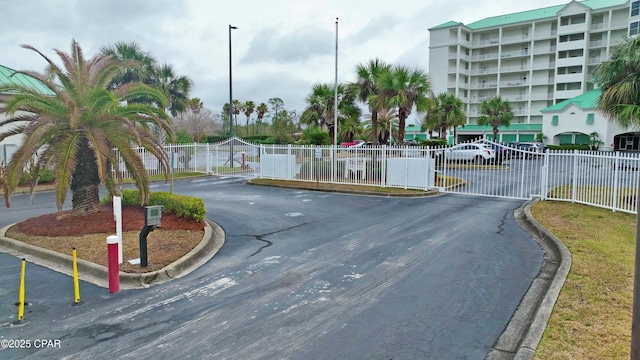 view of street featuring street lighting, a gate, curbs, and a gated entry