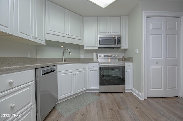 kitchen featuring light wood-style floors, white cabinetry, stainless steel appliances, and light countertops