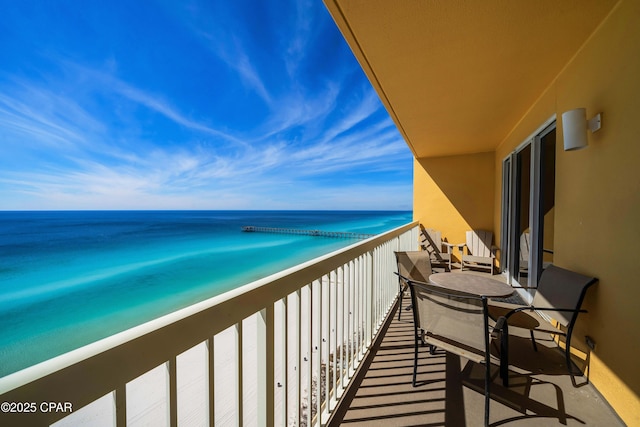 balcony featuring a view of the beach and a water view