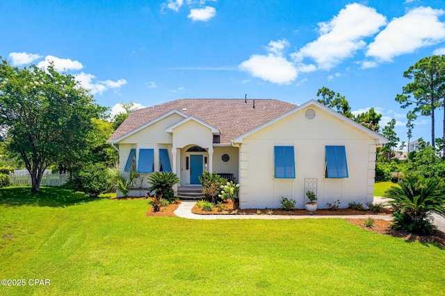 ranch-style home with a front lawn, roof with shingles, and stucco siding