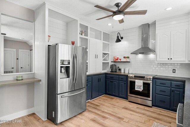 kitchen featuring blue cabinets, appliances with stainless steel finishes, wall chimney range hood, light wood-type flooring, and open shelves