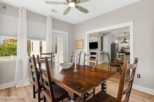 dining area with baseboards, visible vents, ceiling fan, and light wood finished floors