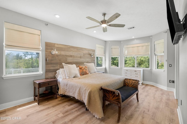 bedroom with light wood finished floors, multiple windows, visible vents, and baseboards