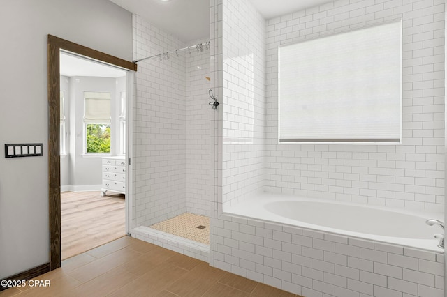 full bath with a relaxing tiled tub, baseboards, a tile shower, and wood finish floors