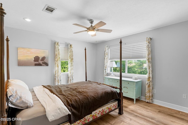 bedroom featuring light wood-style floors, visible vents, multiple windows, and baseboards