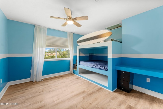 bedroom with attic access, a ceiling fan, baseboards, and wood finished floors