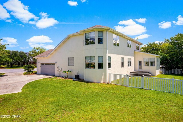 exterior space featuring a garage, fence, a yard, driveway, and stucco siding